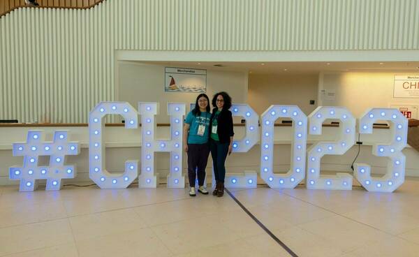 HCI members pose in front of a lighted sign that says, '#CHI2023'